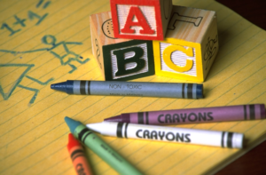 kindergarten abc blocks and crayons on a yellow pad of paper