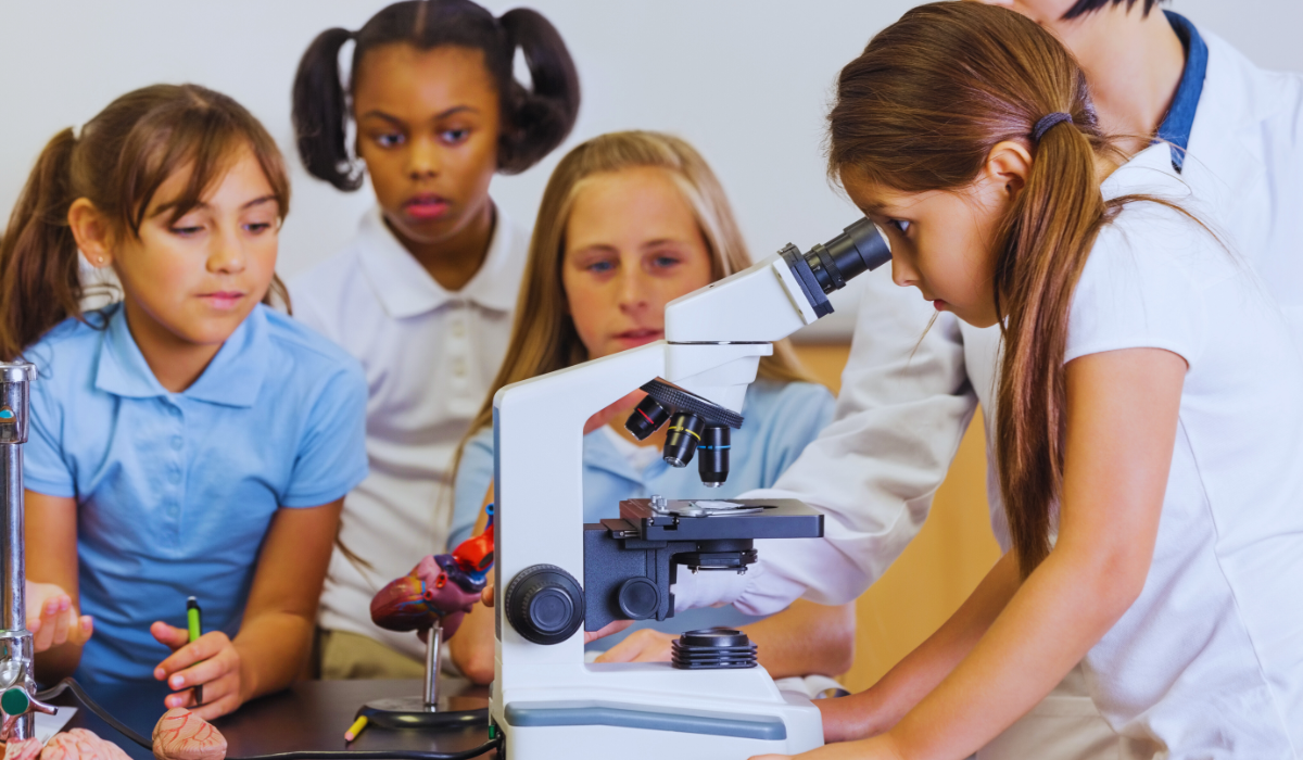 Teacher with 4 students; one looking into a microscope