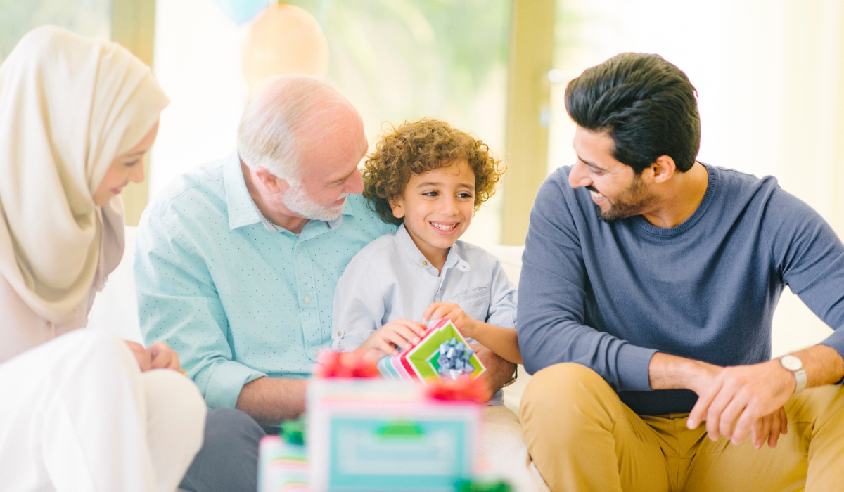 Grandfather holding young boy flanked by Mother and Father. All smiling!