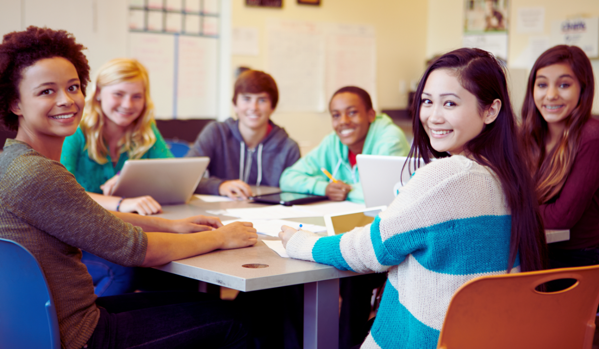 Diverse group of 6 teen students studying around a table