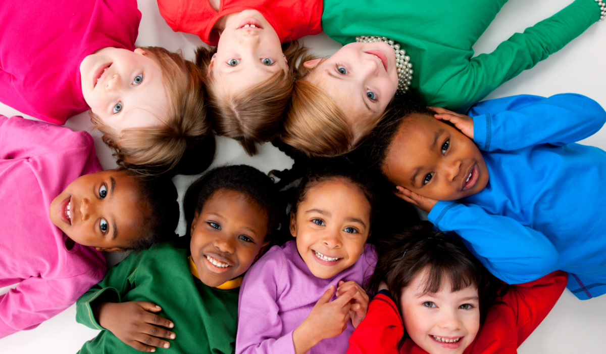 8 racially diverse children smiling, their heads touching in the center of a circle