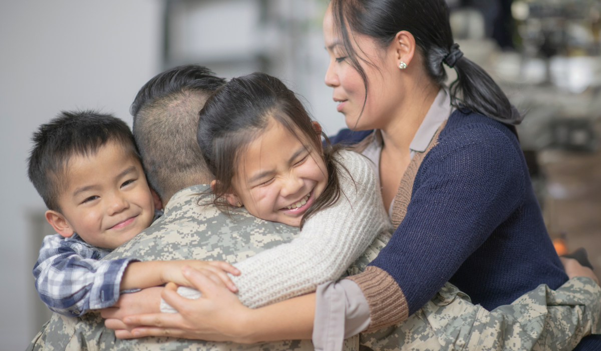 Smiling Mom and two children hugging Dad in Military Uniform
