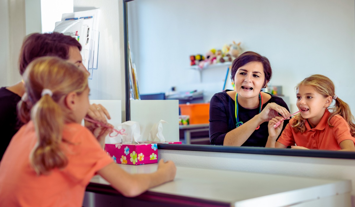 young girl in speech therapy office mirror exercising oral motor skills