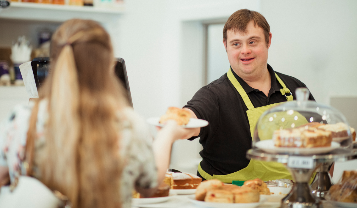 young man with Down Syndrome serving a customer in a coffee shop