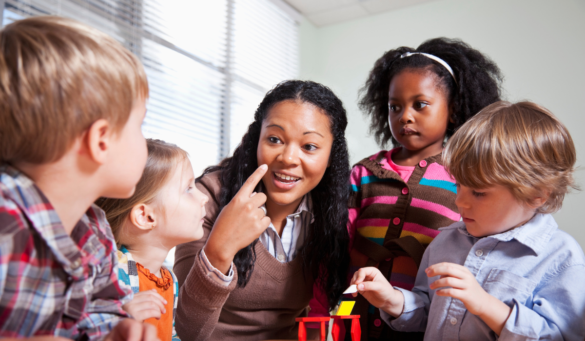 teacher encouraging eye contact and listening while a group of school children are interacting with math manipulatives