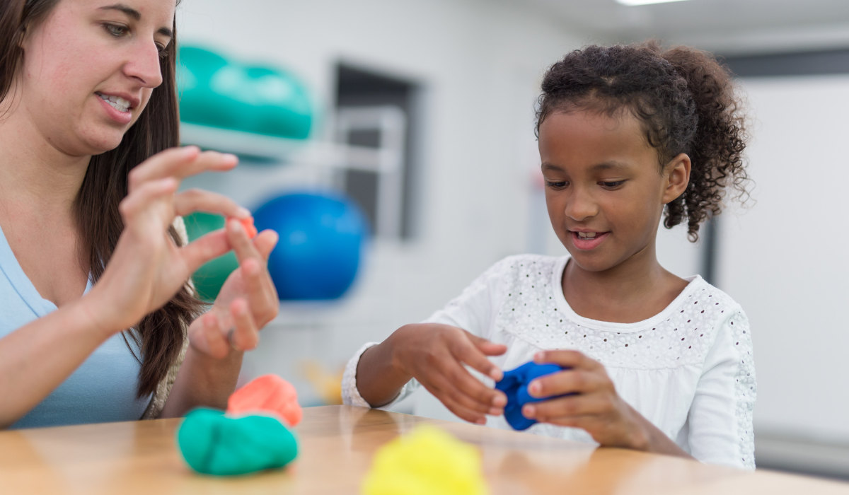 student doing fine motor work with clay with physical or occupational therapist