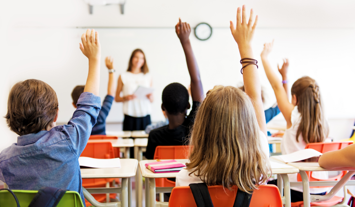 school kids in classroom raising hands appropriately