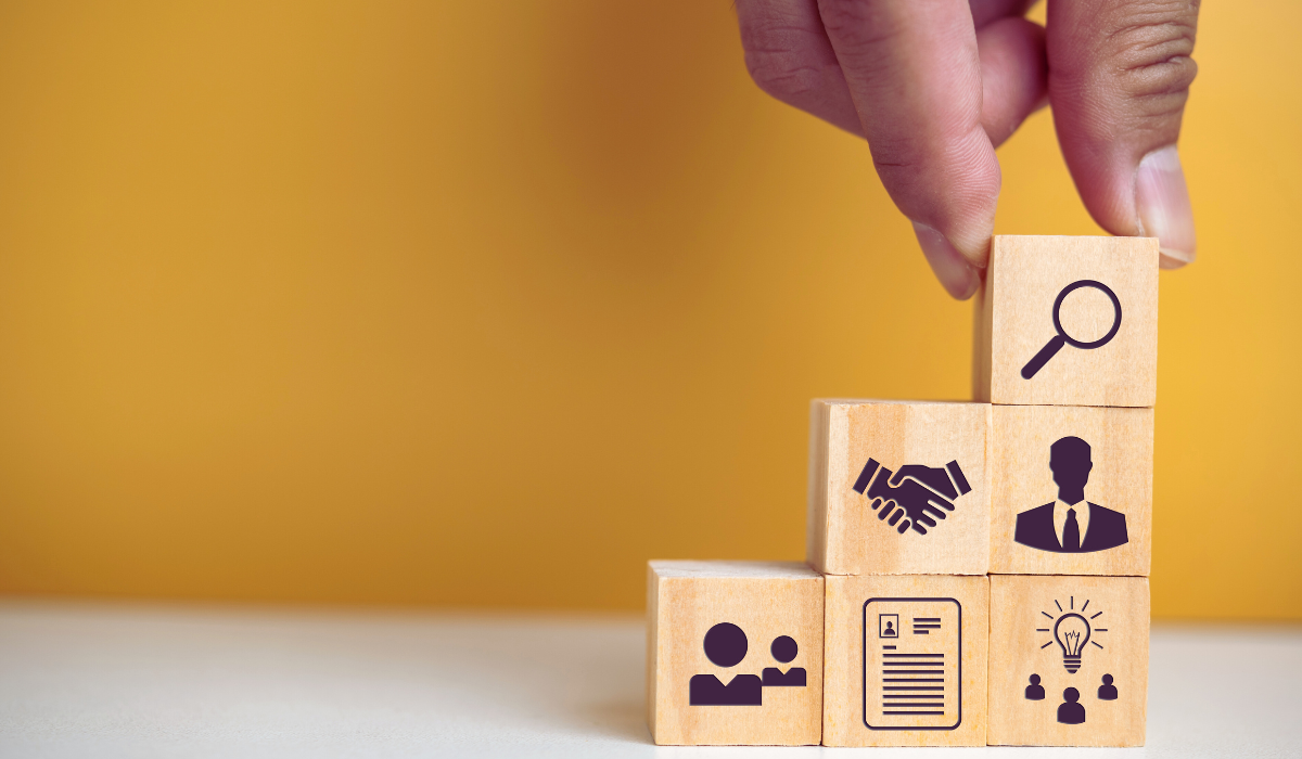 hand stacking blocks with a magnifying glass, a handshake, profile, clipboard, and lightbulb