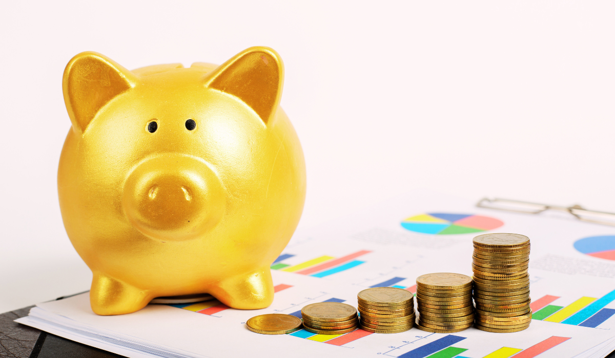 Gold piggy bank and stack of coins on sitting on a colorful bar graph