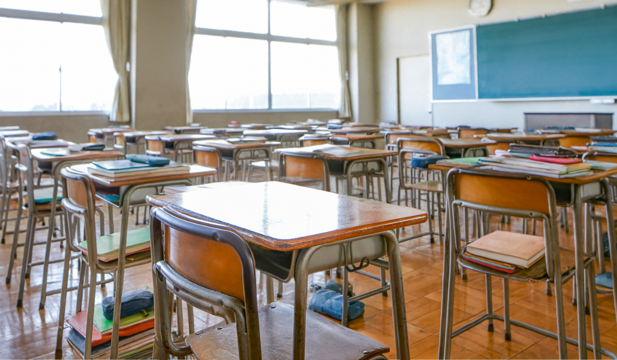 classroom full of desks and supplies, but one desk sits empty