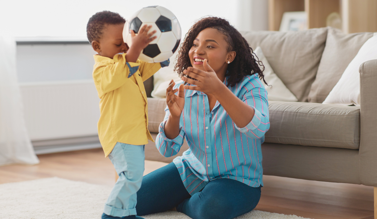 child carrying soccer ball to happy mom