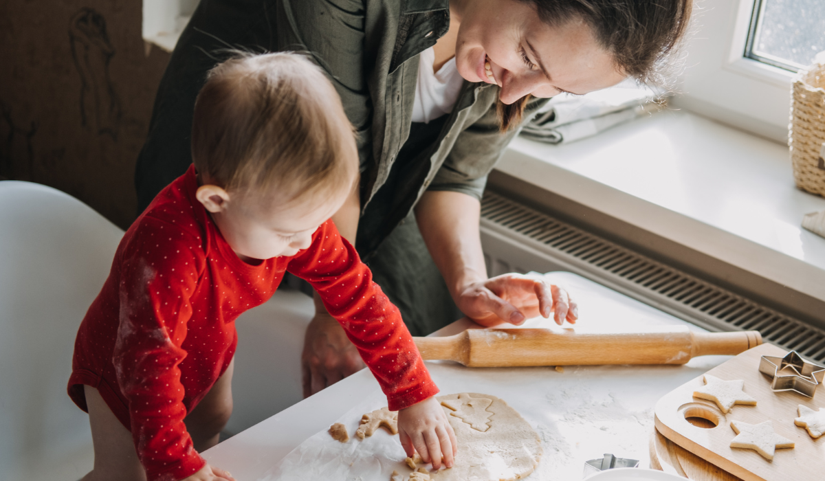 young child in kitchen helping caregiver bake